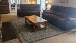 Un salon avec deux canapés, une table basse en bois, un tapis à motifs et un meuble en bois.