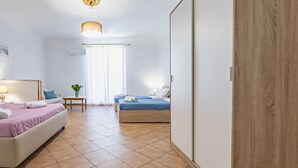 Une chambre d’hôtel moderne, équipée d’un lit, d’une table de chevet, d’une lampe et offrant une vue sur la rue.