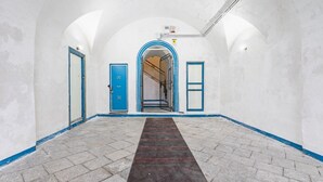 Un couloir avec un tapis à motifs, des portes à cadre bleu et un escalier menant à un étage supérieur.