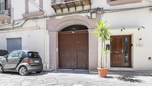 Un bâtiment avec une porte en bois fermée, un pot de fleurs et une voiture garée.