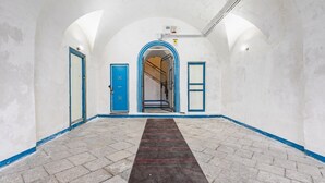 Ein Korridor mit einem gemusterten Teppich, blau gerahmten Türen und einer Treppe, die zu einer oberen Ebene führt.