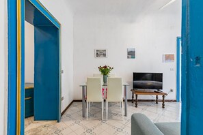 A room with a dining table, chairs, a TV, and a sofa.