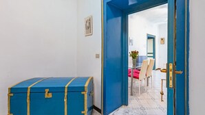 Ein Flur mit einer blauen Tür, der zu einem Essbereich mit Tisch und Stühlen führt.