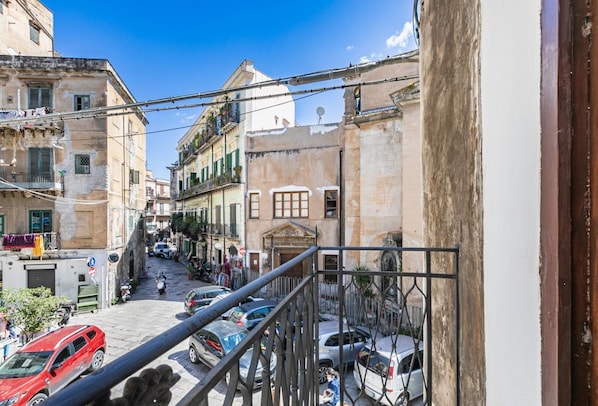 A narrow street with buildings, a visible staircase, and parked cars.