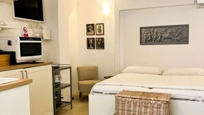 A hotel room with a bed, a chair, a TV, a microwave, and artwork on the wall. - GuestHost - Flaminio MM Comfy Loft - Piazza del Popolo (Roma)
