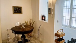 A dining area with a round table, clear chairs, a framed picture on the wall, a window with a view, and a mirror. - GuestHost - Flaminio MM Comfy Loft - Piazza del Popolo (Roma)