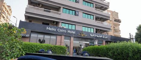 A multi-story hotel building with balconies and a sign indicating it is the Helio Cairo Hotel.