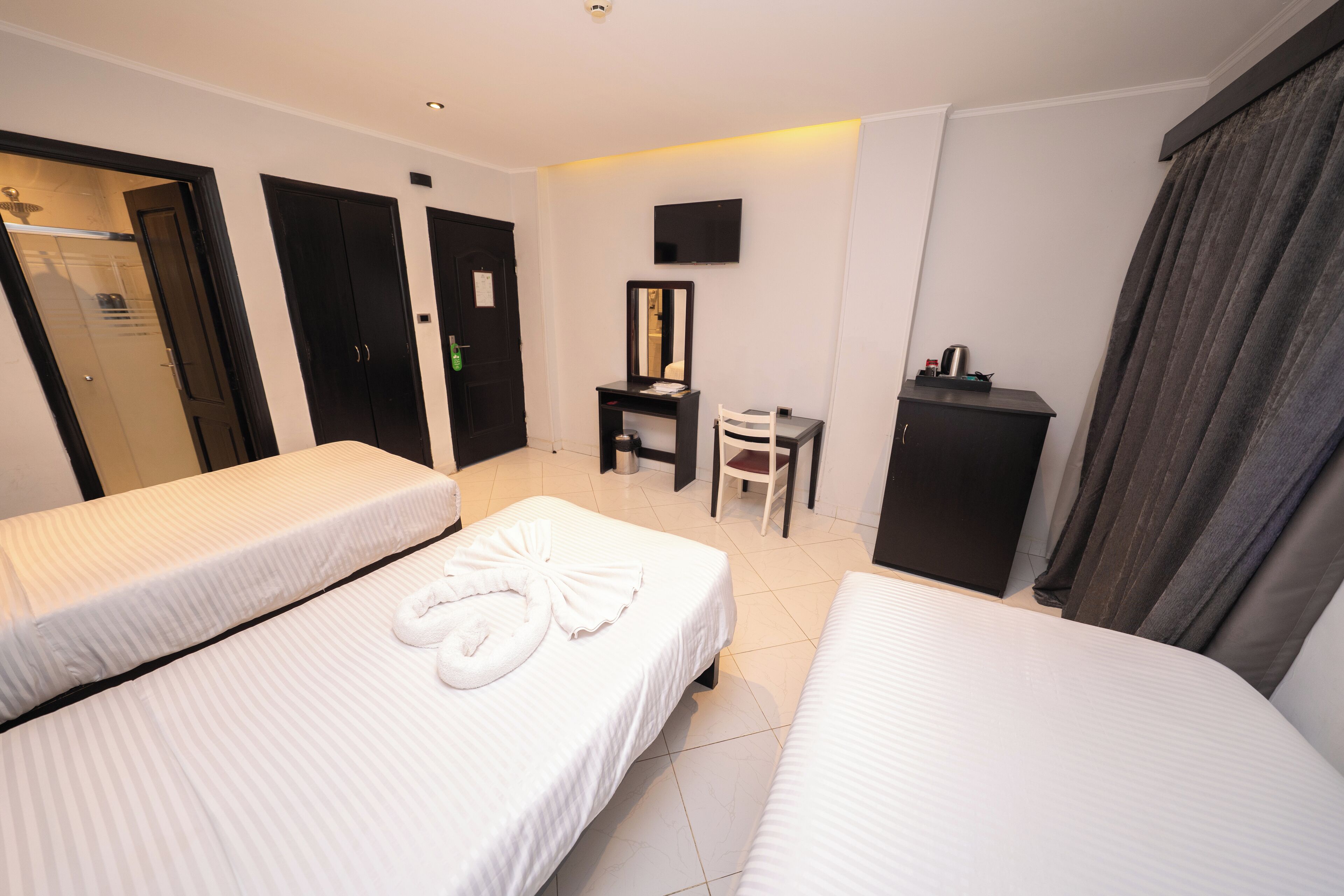 Een hotelkamer met twee bedden, een bureau, een stoel, een televisie en een kledingkast.