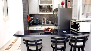 A modern kitchen with a central island, black chairs, and a bowl of fruit. - Very nice apartment in the heart of Alexandria (Alexandria Governorate)