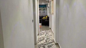 A hallway with a patterned carpet, white walls, and recessed lighting. - Very nice apartment in the heart of Alexandria (Alexandria Governorate)