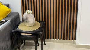A room with a black TV on the wall, a grey sofa with a yellow pillow, and a small black table with a woven basket. - Very nice apartment in the heart of Alexandria (Alexandria Governorate)