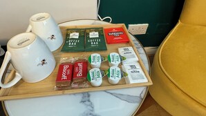 Una bandeja con tazas de café, paquetes de café, galletas, leche y azúcar sobre una mesa de mármol.