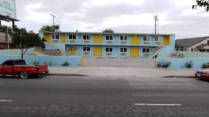Un motel composé d’un bâtiment à deux étages, d’un parking et d’un camion rouge garé dans la rue.