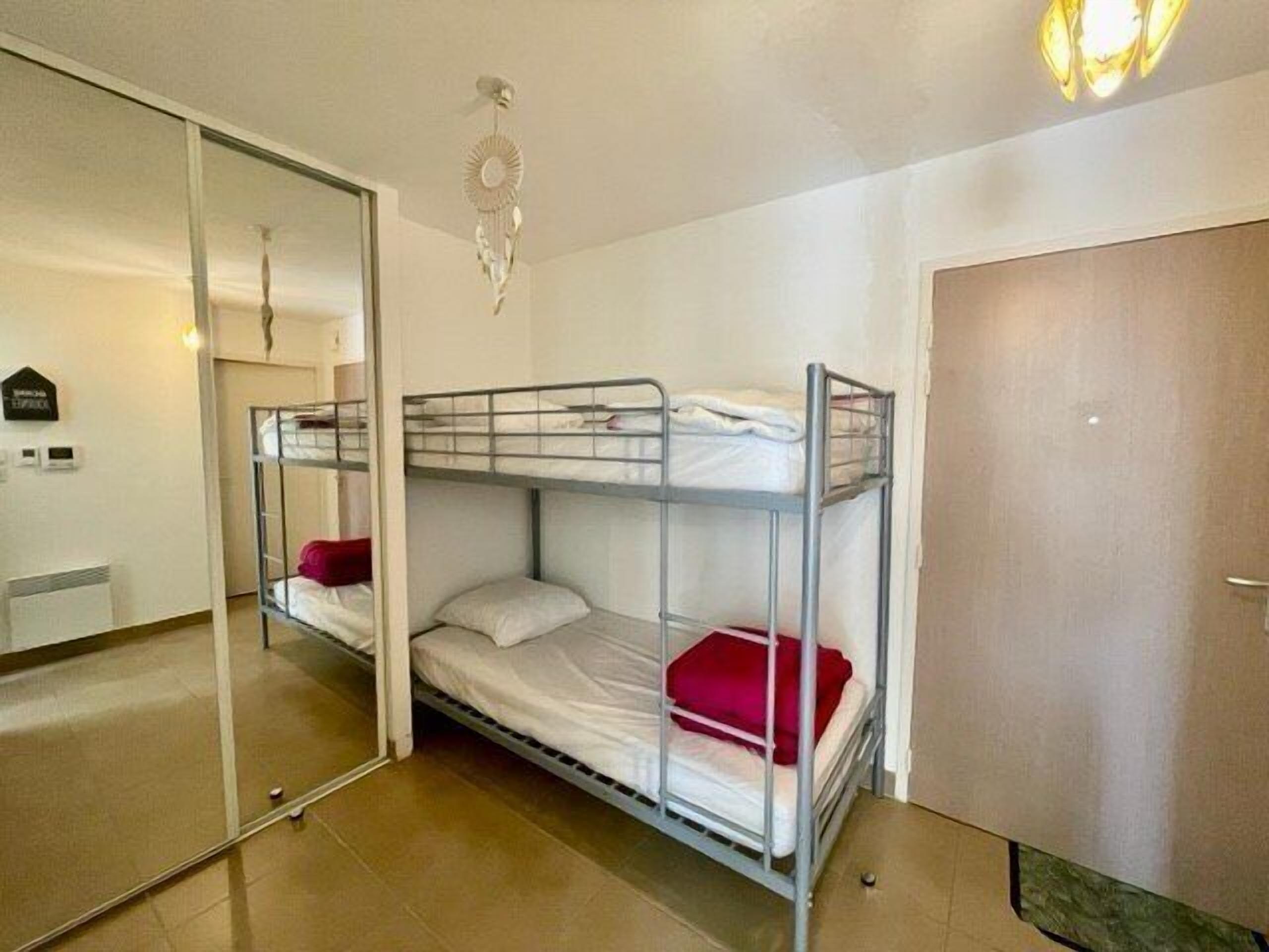 A bunk bed room with a mirror, a door, and a ceiling light fixture.