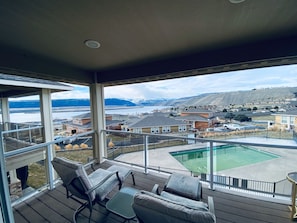 Un balcon avec coin salon extérieur, une piscine et une vue sur un quartier résidentiel et les montagnes.