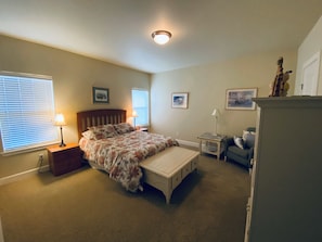 Une chambre à coucher comprenant un lit, des tables de chevet, une commode, une chaise et une coiffeuse.