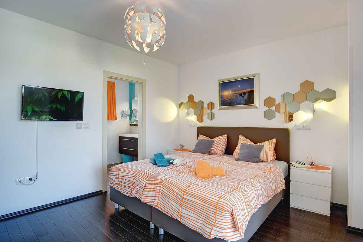 A modern bedroom with a large bed, a TV, a unique wall light, and a framed picture.