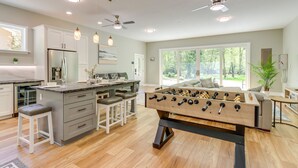 A spacious kitchen with a central island, bar stools, and a foosball table. - Riverfront Hayesville Retreat: Fishing & Kayaking! (Hayesville)