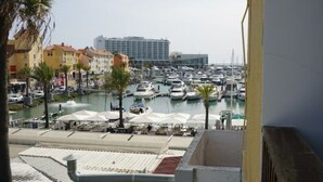 A marina with boats docked, a water fountain, and a row of buildings in the background. - Modern 2 bedroom Vilamoura Marin (Quarteira)