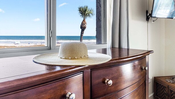 Een houten dressoir met een geweven hoed en een palmboom buiten het raam.