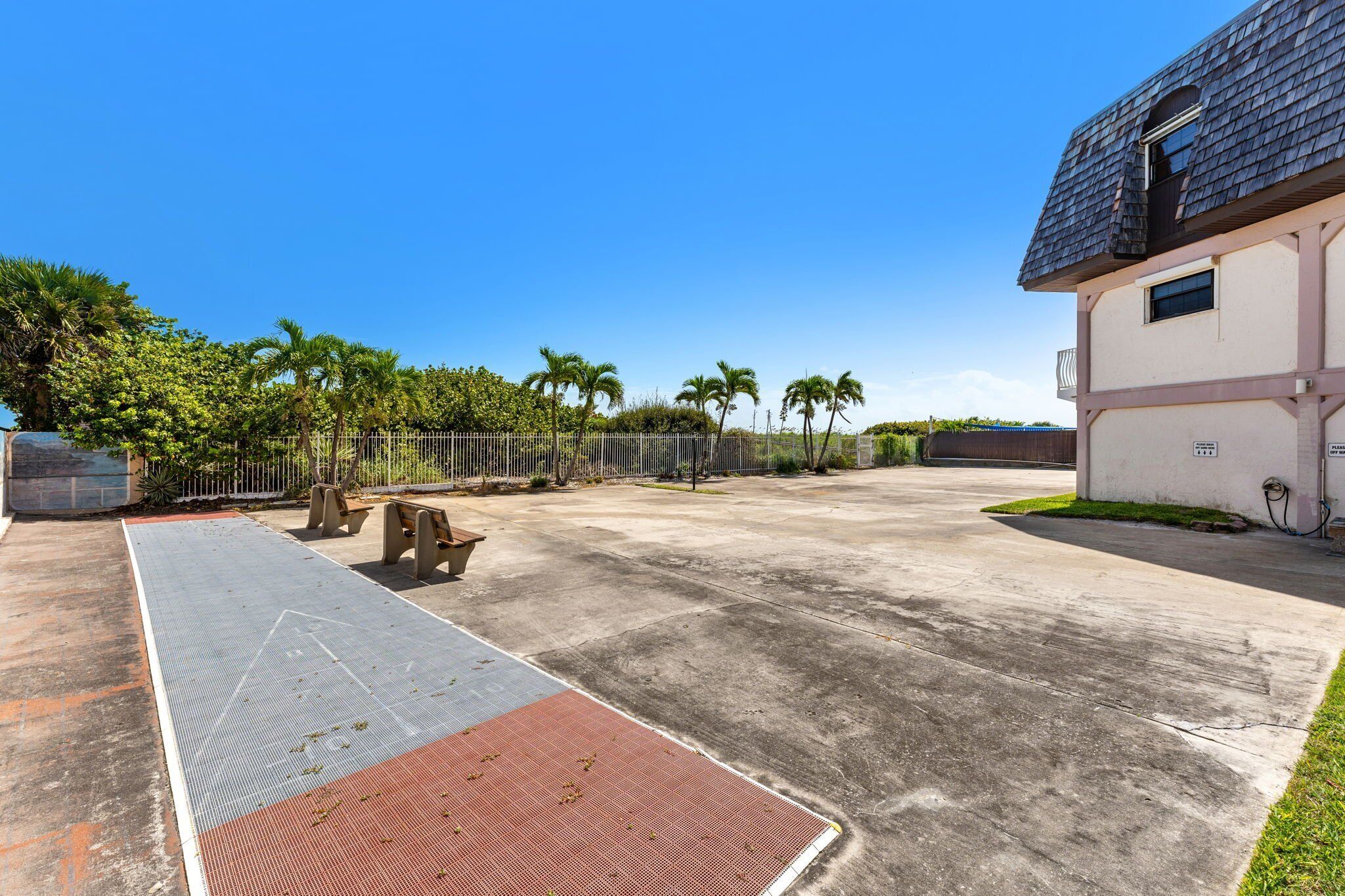Un área exterior amplia con patio de concreto, una rampa para facilitar el acceso y un edificio con techo oscuro.