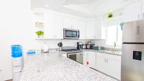 A modern kitchen with white cabinets, a stainless steel refrigerator, a microwave, and a water dispenser. - Residence 4 (4 Bed 3.5 Bath By FMI Rentals) (Puerto Peñasco)