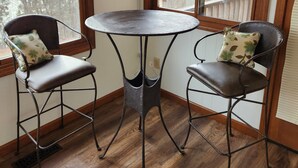 A corner seating area with two chairs and a small table, wooden flooring, and large windows with a view of trees and buildings. - Cottage at Lake Cumberland; 6m walk to water at Clearwater public boat ramp (Nancy)