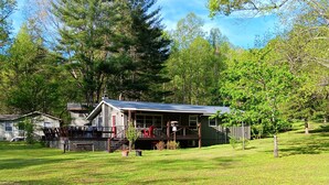 A house with a porch, a covered outdoor seating area, and a fenced yard. - Twin Creeks on the Cullasaja (Franklin)