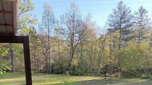 A wooden deck with a railing, leading to a grassy yard with trees and a clear sky. - Twin Creeks on the Cullasaja (Franklin)
