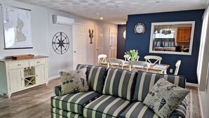 Un salon chaleureux avec un canapé à rayures, une carte accrochée au mur et un coin repas comprenant des chaises et une table.
