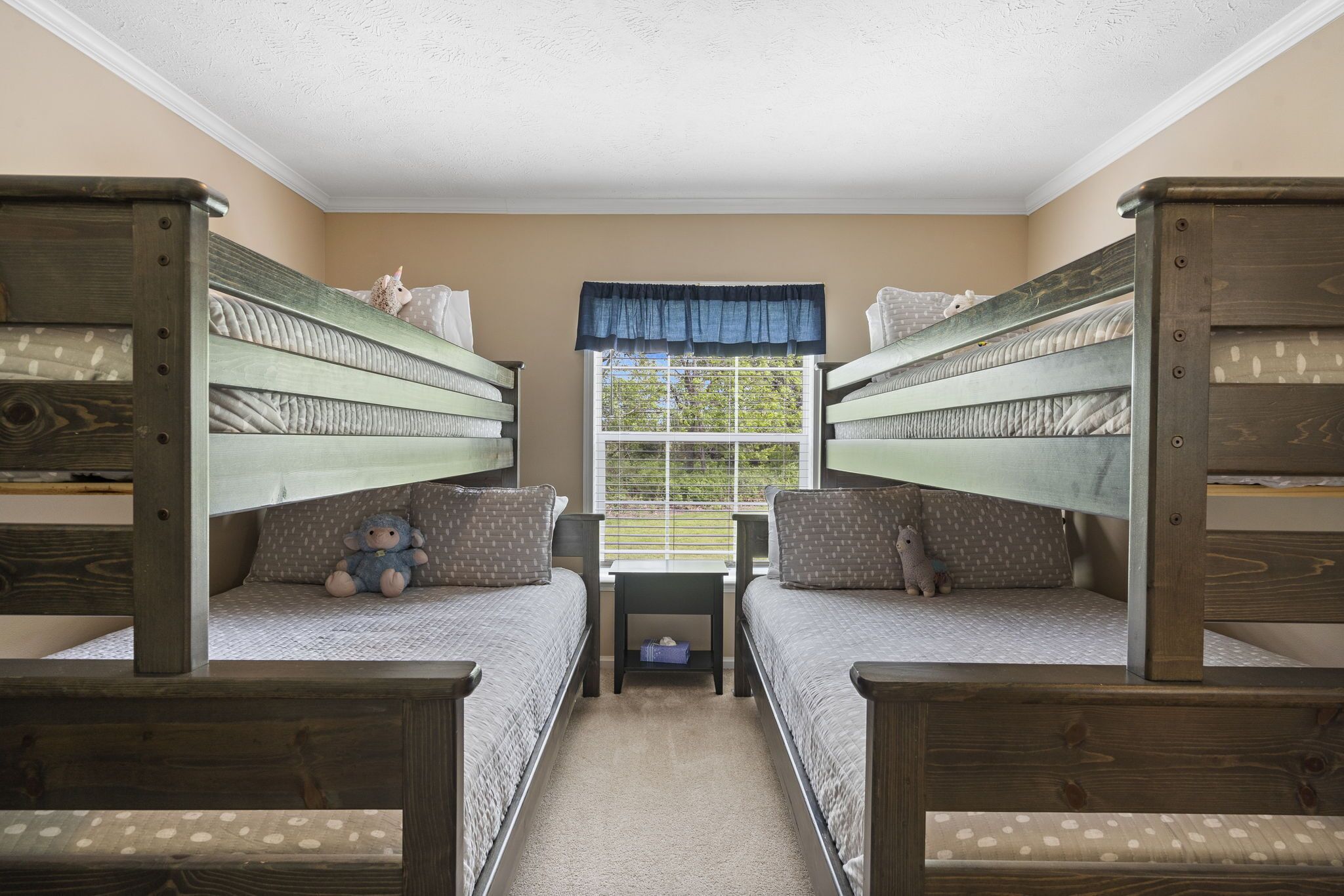 Une chambre avec des lits superposés, une petite table et une fenêtre donnant sur un paysage verdoyant.
