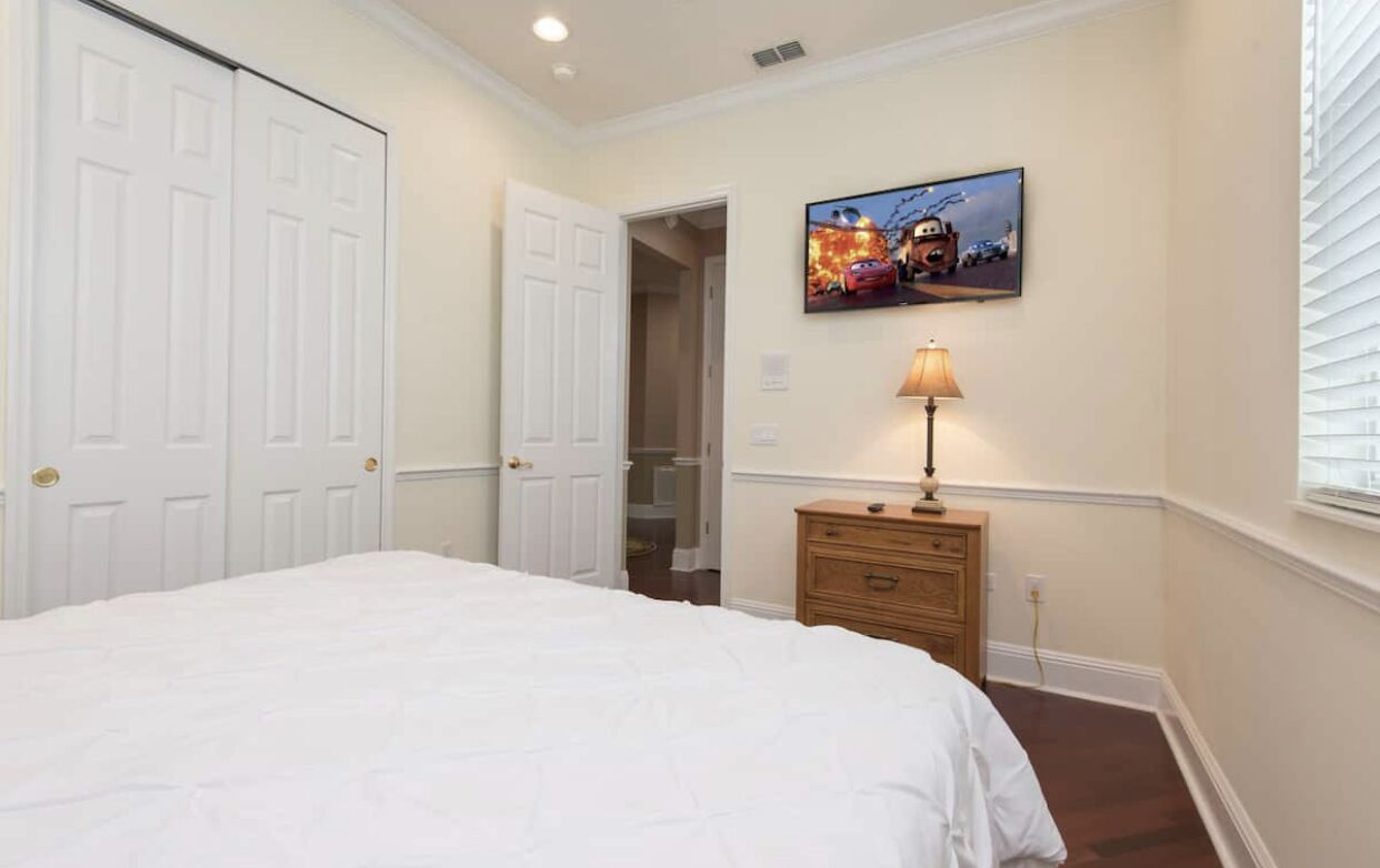 A bedroom with a bed, a dresser, a lamp, and a painting on the wall.