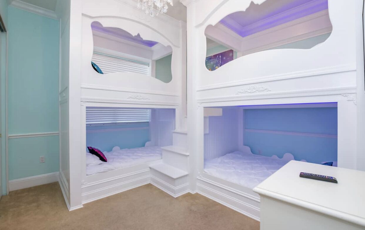 A children's room with bunk beds, a desk, and a ceiling light fixture.