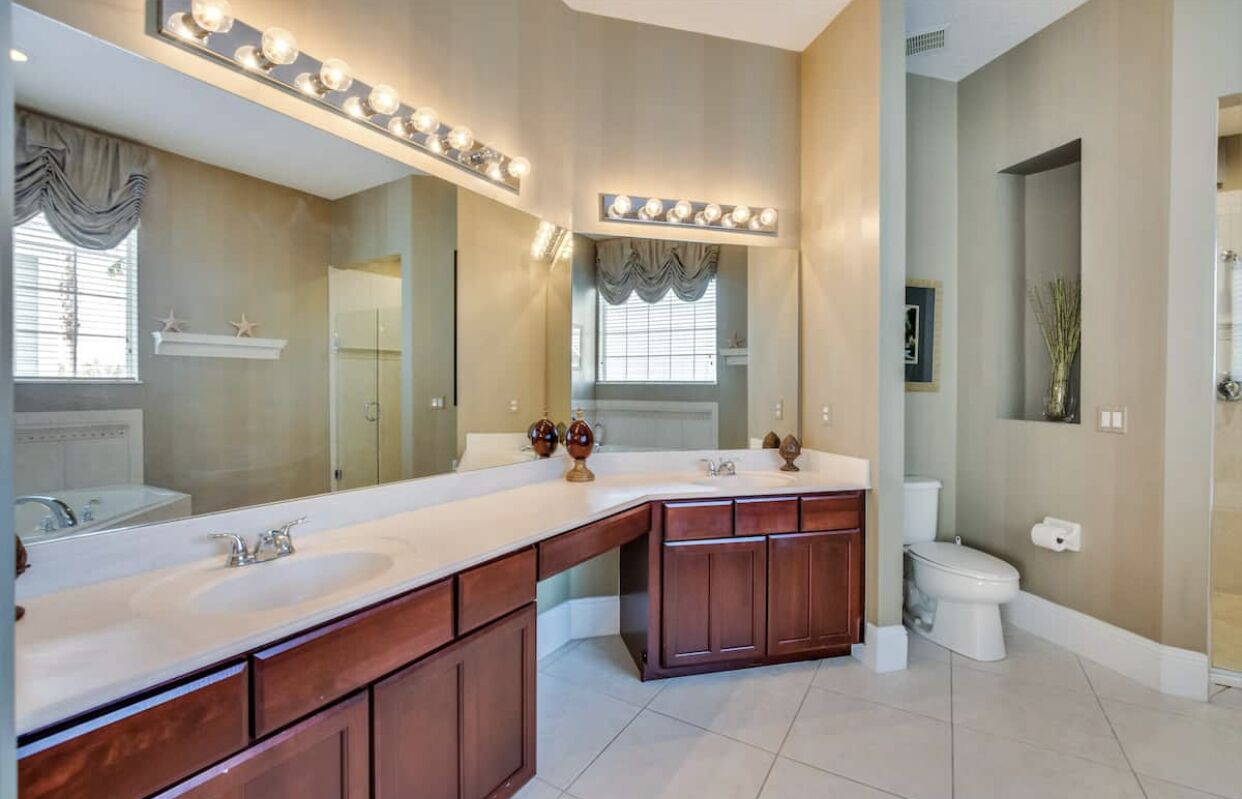 Een badkamer met een groot wastafelmeubel, dubbele wastafels en een toilet.