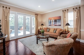 A spacious living room with a large sofa, a coffee table, and a fireplace. There is a sliding glass door leading to a balcony.