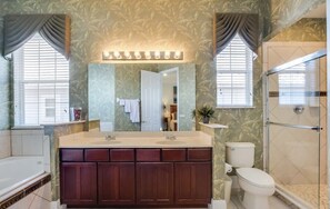 A bathroom with a double sink vanity, a large mirror, a toilet, and a walk-in shower. - Disney theme 5 bed 5 bath with pool (Kissimmee)