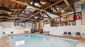 Una piscina cubierta con techo de madera y vistas al cielo a través de un tragaluz.