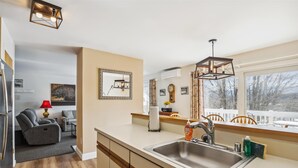Una cocina moderna con un lavamanos grande, armarios de madera y una ventana con vistas a árboles.
