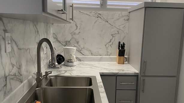 Una cocina moderna con encimera de mármol, pileta de acero inoxidable y mueble gris.