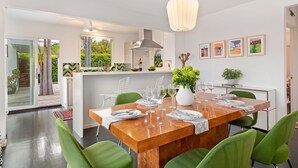 A modern kitchen with a wooden dining table set for six, surrounded by green chairs. - Newly Remodeled Charming and Contemporary Home (Santa Barbara)