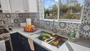 Une cuisine moderne dotée d’un évier encastré, d’une cuisinière et d’une fenêtre donnant sur un jardin.