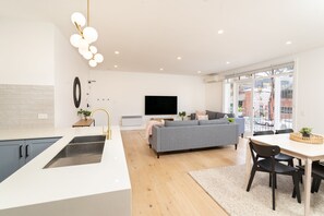 Enjoy a spacious living area with a sofa, dining table, and large flat-screen TV.