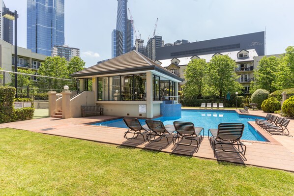 Relax by the pool with a view of the city skyline, surrounded by lounge chairs and a shaded pavilion.