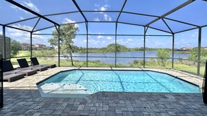 Una piscina techada con vistas a un lago y follaje circundante.