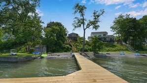 A wooden dock extending into a body of water with houses in the background.