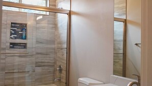 Un baño moderno con cabina de ducha de vidrio, inodoro y tocador con espejo.