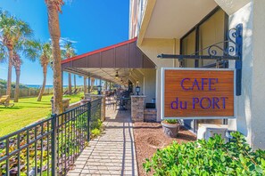 A covered outdoor seating area with a sign reading 'CAFE du PORT'. - Ocean Reef 1503 (Myrtle Beach)