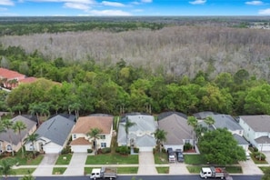 Un quartier résidentiel avec des maisons, un ciel dégagé et une forêt en arrière-plan.