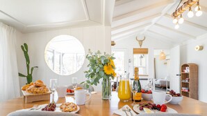 A breakfast setting with a wooden table, plates of food, glasses, and a vase with flowers.