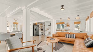 A spacious living area with a sofa, chairs, and a kitchen in the background.